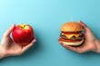 © tanapat - A hand holds an apple on the left, while another hand holds a burger on the right, set against a light blue background.