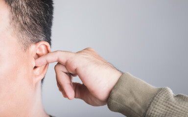 Close-up of a man using his finger to scratch inside his ear, highlighting the risks of ear irritation and injury from ear picking. This image emphasizes the importance of safe ear care practices