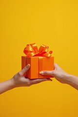 Wall Mural - Vibrant orange gift box with a shiny ribbon exchanged between hands against a bright yellow background