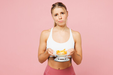 Poster - Young sad woman she wear white top casual clothes hold scales with small portion of french fries potato isolated on plain pink background. Proper nutrition healthy fast food unhealthy choice concept.