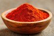 © Rangga Bimantara - A bowl filled with vibrant red spice, likely paprika or chili powder, on a wooden surface.
