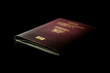 © DBFilms - An isolated image of a passport with a maroon cover, slight signs of wear visible on the edges, lying horizontally against a dark background.