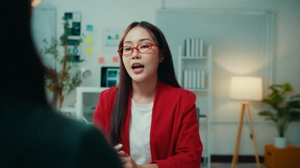 Aufkleber - Asian businesswoman wearing a red blazer is speaking passionately with her hands while explaining a business strategy to her team during an office meeting