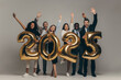 © gstockstudio - Group of happy business people holding 2025 numbers while celebrating New Year on studio background