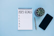 © olyphotostories - 2025 New Year goals background with blank notebook, pen, smartphone and plant. Space for text. Top view. Christmas to-do list or wish list