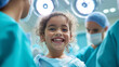 © Curioso.Photography - Young child smiling brightly in a hospital setting, surrounded by medical staff in scrubs, conveying a hopeful and positive atmosphere.
