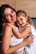 © dvulikaia - Portrait of mother and daughter hugging each other and looking to the camera