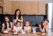 © dvulikaia - A young mother cooks cheeseecake  with her daughters. Mom teaches her daughters to cook.