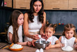 © dvulikaia - A young mother cooks cheeseecake  pie with her daughters. Mom teaches her daughters to cook.