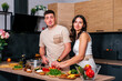 © dvulikaia - Happy man cooking salad for his happy young wife at the kitchen in the morning.