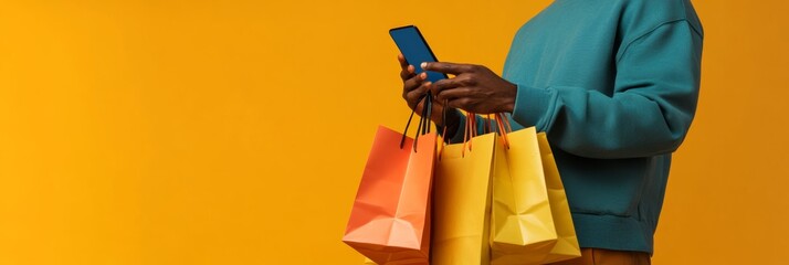 Poster - Unrecognizable black man using mobile phone and holding colorful shopping bags on yellow background, making online purchases and enjoying e commerce experience