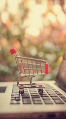 Poster - Miniature shopping cart is standing on a laptop keyboard, symbolizing the concept of online shopping, e commerce, and convenient delivery in the digital age