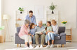 © Studio Romantic - Big happy family of young parents,senior grandparents and children sitting on sofa at home looking through a family photo album enjoying good memories on weekend. Family leisure concept.