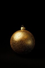 Poster - A shiny gold Christmas ornament against a dark black backdrop, perfect for holiday decorations and celebrations