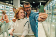 © Zamrznuti tonovi - Happy couple taking a selfie while grocery shopping in supermarket