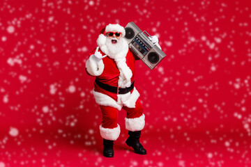 Wall Mural - Full body size photo of retired old man grey beard hold boombox shoulder open mouth show horns wear santa costume sunglass headwear leather black boots isolated red color background