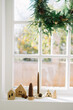 © Adrian Cotiga/Stocksy - Holiday wreath and village display on bright window
