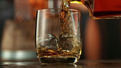 Poster - Pouring whiskey into glass full of ice cubes.