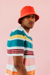 © BONNINSTUDIO/Stocksy - Man wearing red bucket hat and colorful shirt posing on studio