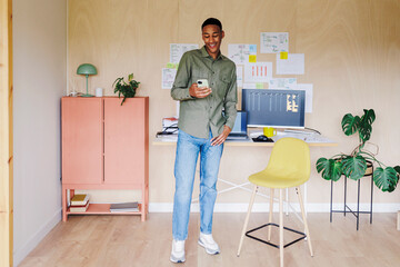 Programmer smiling and checking his phone in home office