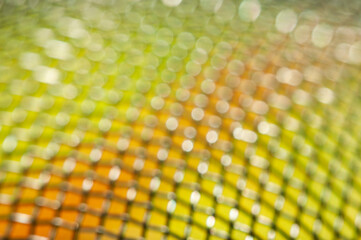 Wall Mural - a close-up of a golden, sparkly mesh with light shining through