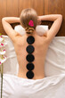 © Prostock-studio - Spa stone massage concept. Girl on massage rustic wood table, top view