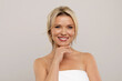 © Anastasiya - Portrait of cheerful attractive middle aged blonde woman smiling at camera, posing topless on grey studio background, demonstrating glowing perfect skin, copy space. Cosmetology concept. High quality