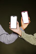 © BONNINSTUDIO/Stocksy - Two women showing smartphones with white screen on dark background