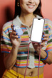 © BONNINSTUDIO/Stocksy - Woman holding smartphone with blank screen and earphones