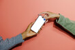 © BONNINSTUDIO/Stocksy - Two people holding smartphone with blank screen on coral background