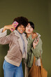 © BONNINSTUDIO/Stocksy - Two happy friends taking a selfie together posing with mobile phones
