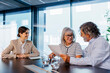 © BONNINSTUDIO/Stocksy - Senior couple reviewing documents with financial advisor