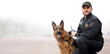© Pixel-Shot - Male police officer with dog patrolling city street