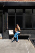 © Adrian Rodd/Stocksy - A female tourist relaxes outside a café in the streets of New York