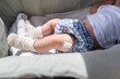 © Raul Navarro/Stocksy - Baby lying down wearing knitted socks showing vaccination site