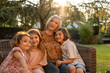 © Stephanie Tamir/Stocksy - A grandma posing with her grandchildren's at sunset in the backyard