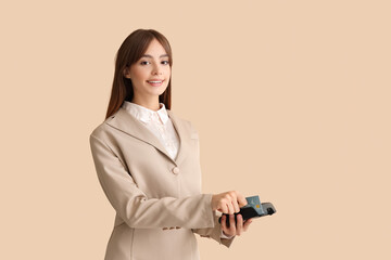 Canvas Print - Beautiful young businesswoman with credit card paying via payment terminal on beige background