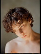© Irina Polonina/Stocksy - Young Man With Curly Hair in Soft Natural Light