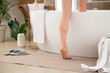 © Pixel-Shot - Woman getting into bathtub from mat at home, back view