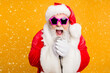 © deagreez - Jolly christmas x-mas performance from funky santa claus Modern crazy grandfather in red fairy north-pole creature costume sing song on stage hold microphone scream isolated yellow color background