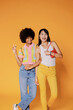 © BONNINSTUDIO/Stocksy - Two stylish women posing on orange background