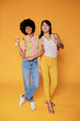 © BONNINSTUDIO/Stocksy - Two stylish women posing on orange background