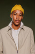 © BONNINSTUDIO/Stocksy - Man wearing yellow beanie and beige jacket looking at camera