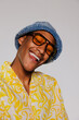 © BONNINSTUDIO/Stocksy - Man wearing sunglasses and bucket hat laughing in studio