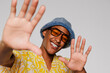 © BONNINSTUDIO/Stocksy - Cheerful man wearing sunglasses and bucket hat in studio