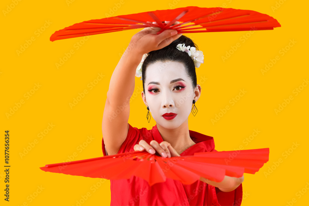 Beautiful young geisha with fans on yellow background