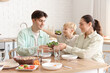 © Pixel-Shot - Parents with their little son eating Fajita at table in kitchen
