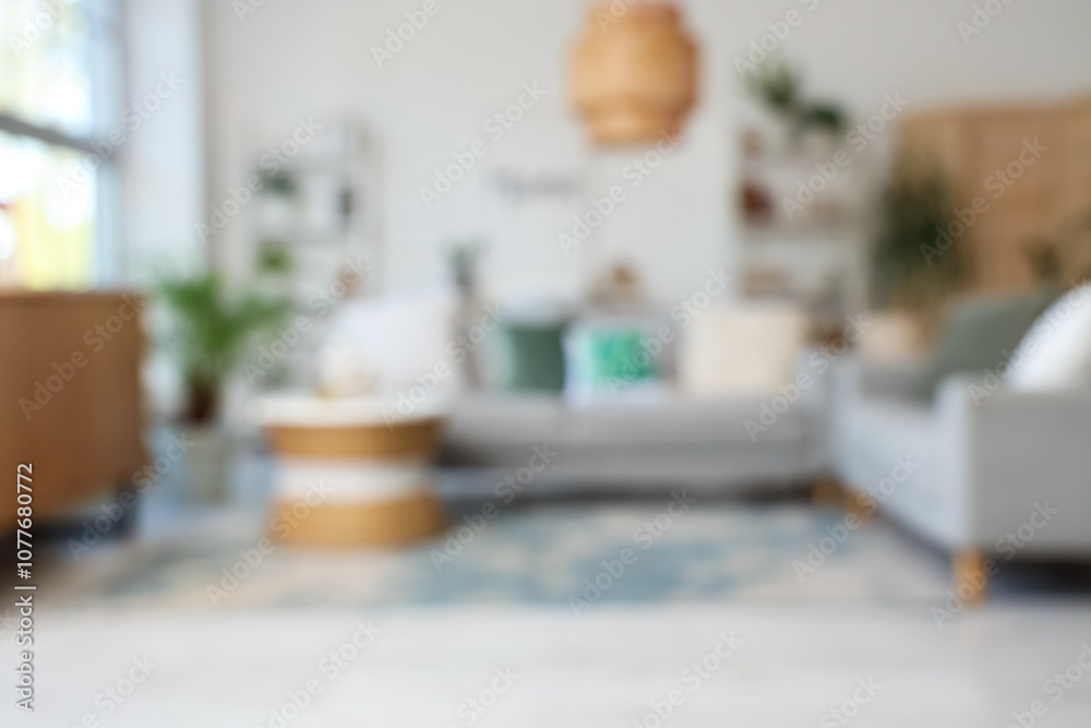 Blurred view of living room with grey sofas, shelf units and plants