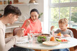 © Pixel-Shot - Little boy with his parents eating Fajita at table in kitchen