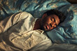 © Steven - Young Black man peacefully sleeping on a blue pillow in soft morning light, wearing a white shirt, with a calm and serene expression.
